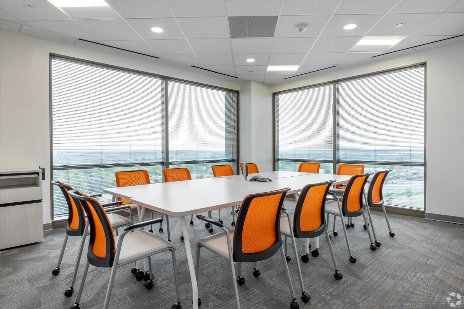 Conference Room 1 boardroom with orange chairs and wraparound windows overlooking the horizon