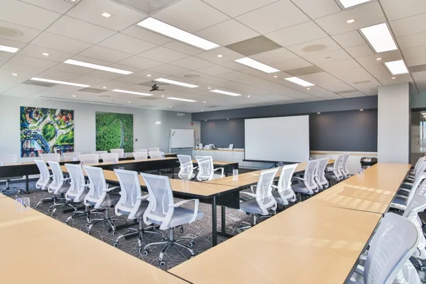 Training Room A set in a U-shape with white mesh chairs and a large presentation screen